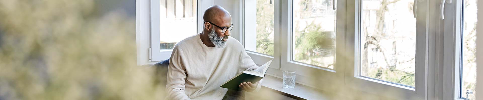 Man sitting at window and reading