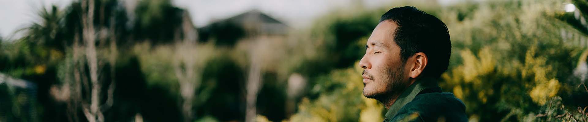 Man sitting in garden with eyes closed