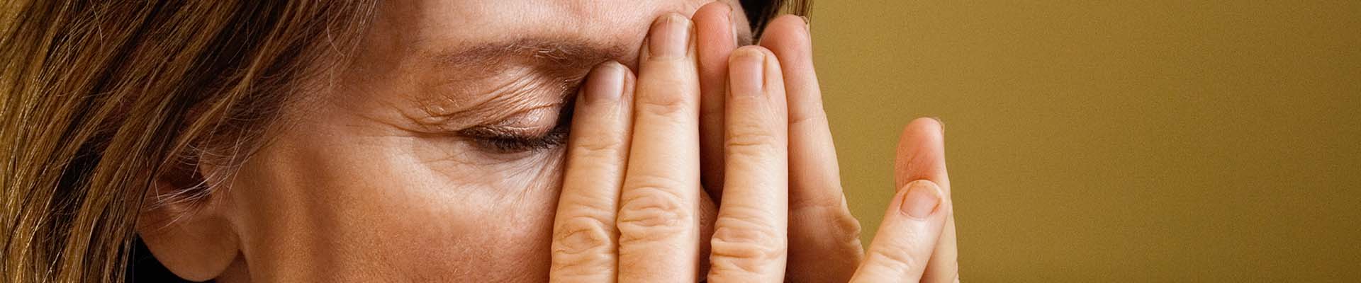 Stressed woman, covering face with hands